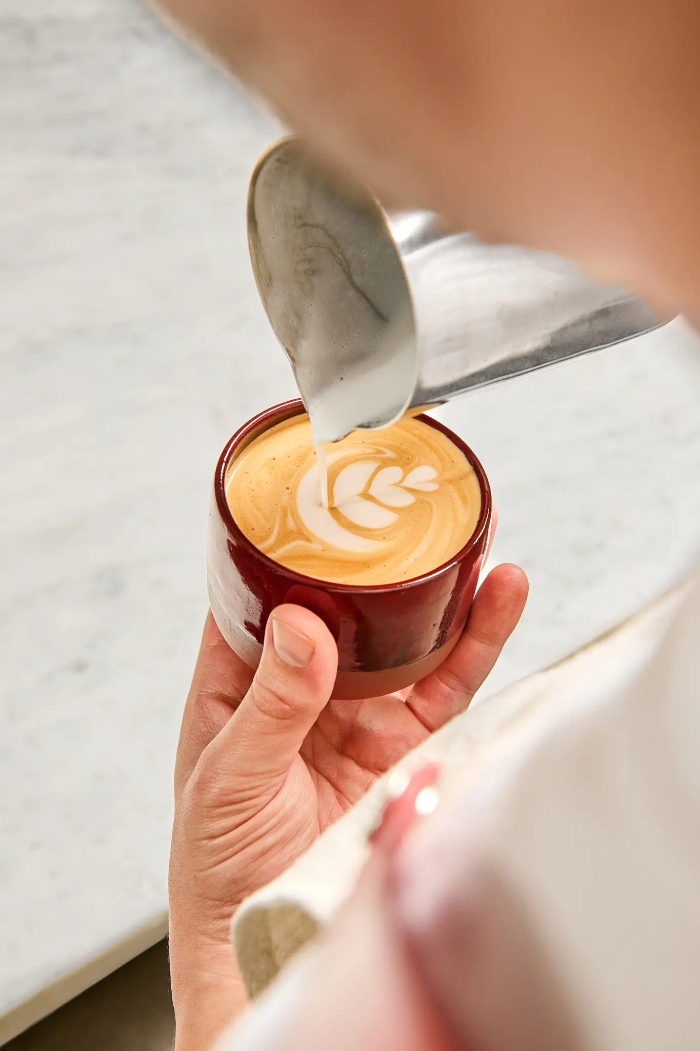 Detail latte art – ručně připravená káva s jemným srdcem z mléčné pěny.